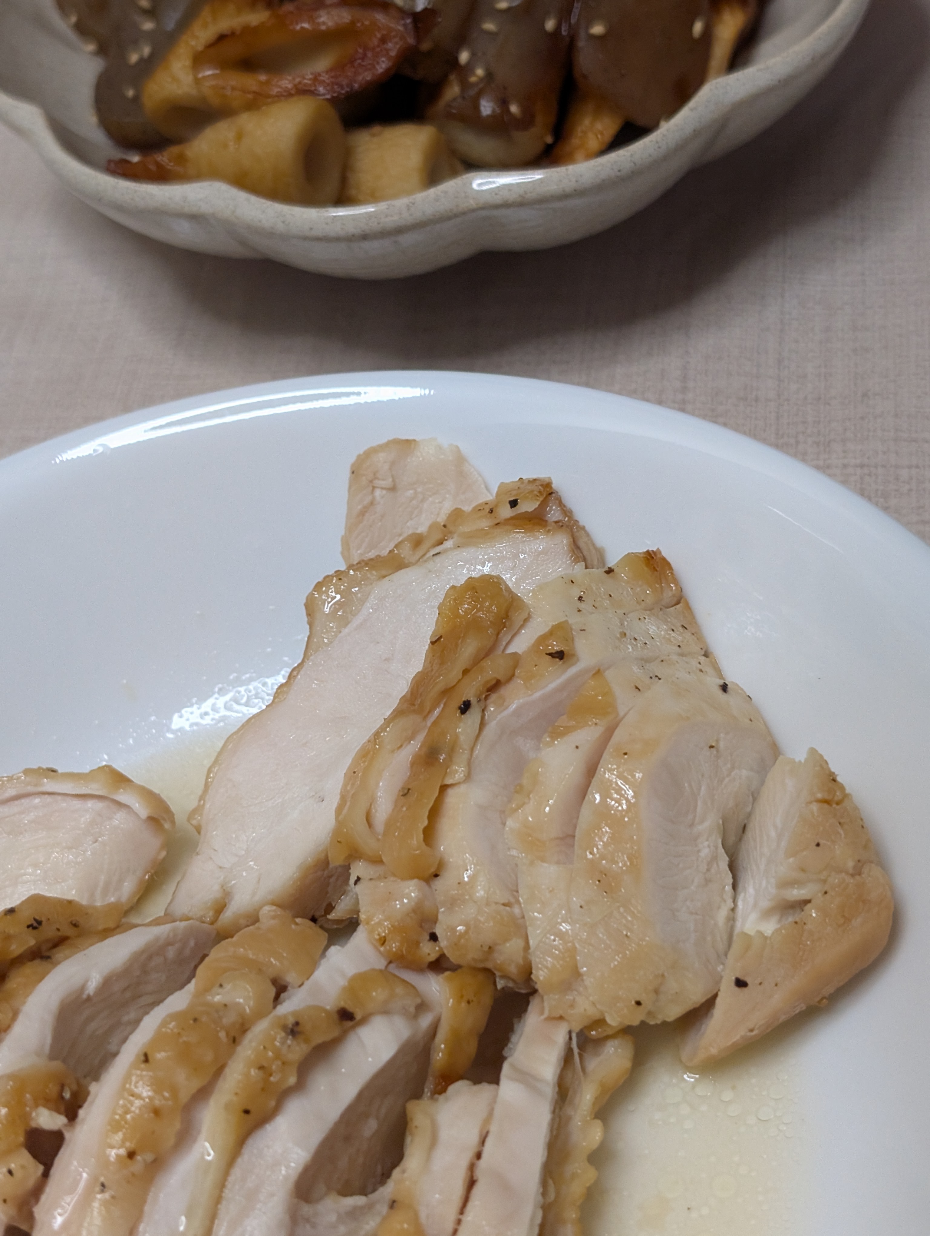 白い皿に並んだ鶏肉の照り焼きと、奥の小鉢の煮物