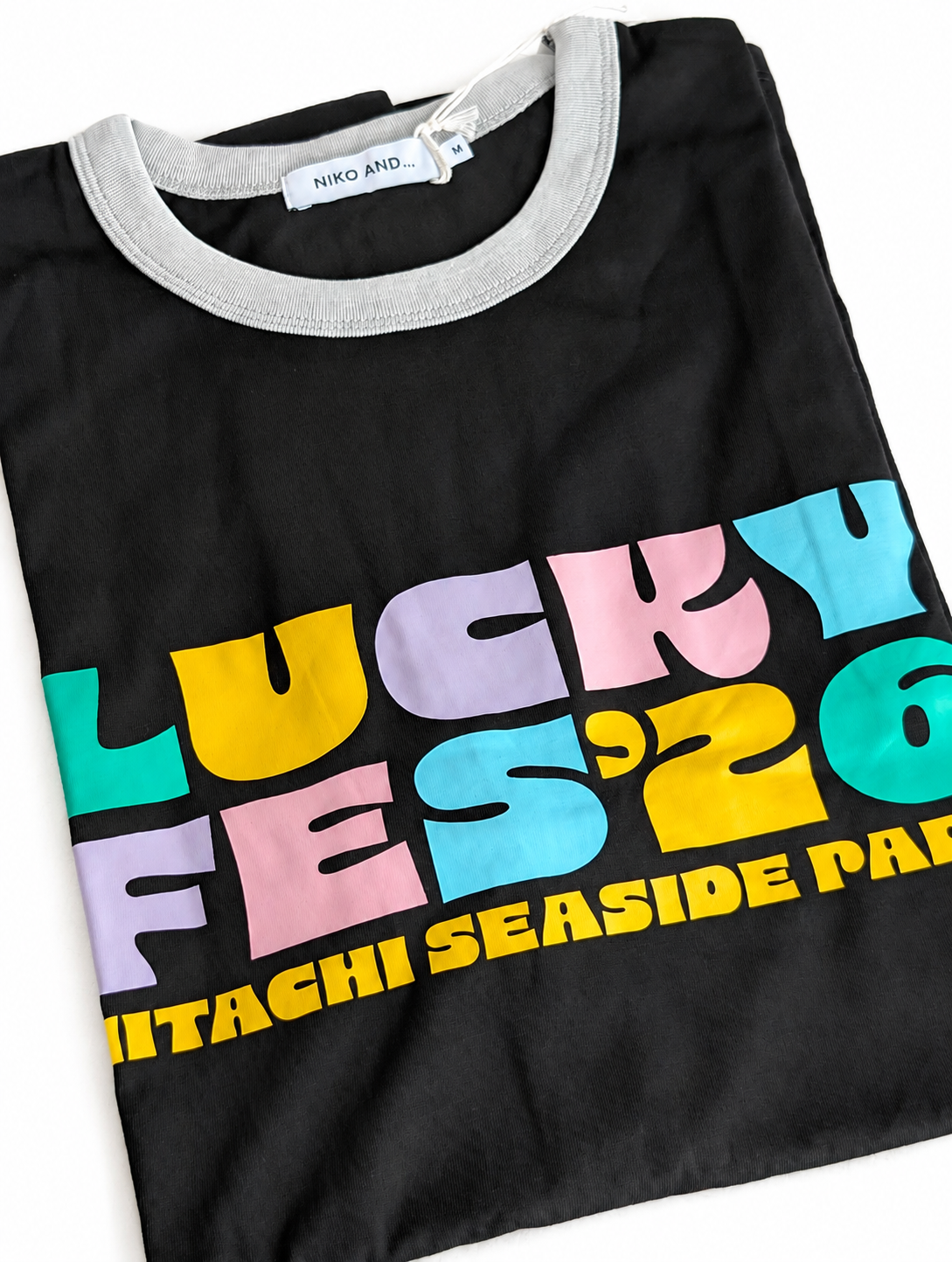 LUCKY FES ‘26 HITACHI SEASIDE PARK とパステルカラーでプリントされた黒いTシャツ