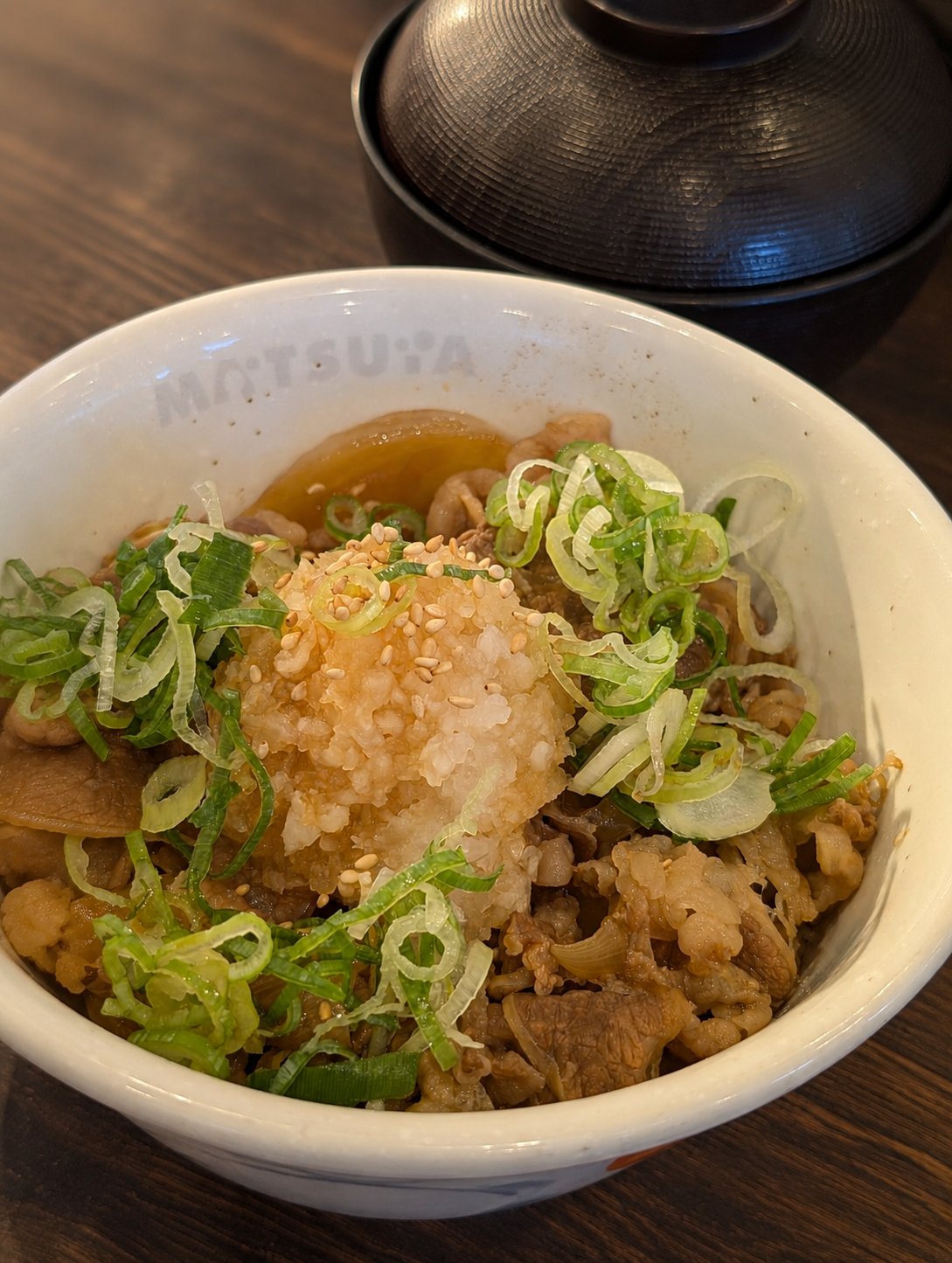 大根おろしと青ネギと白ゴマがのった松屋のおろし牛めし。丼にMATSUYAの刻印、奥に味噌汁の椀