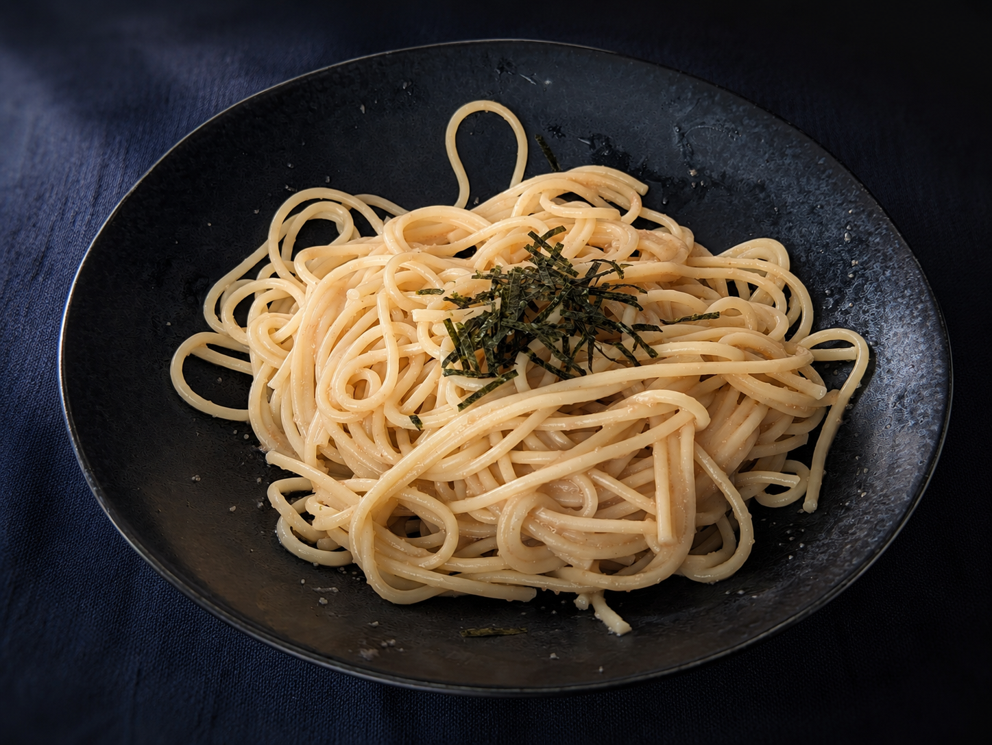 黒い皿に盛ったたらこスパゲッティ。上に刻み海苔をのせている