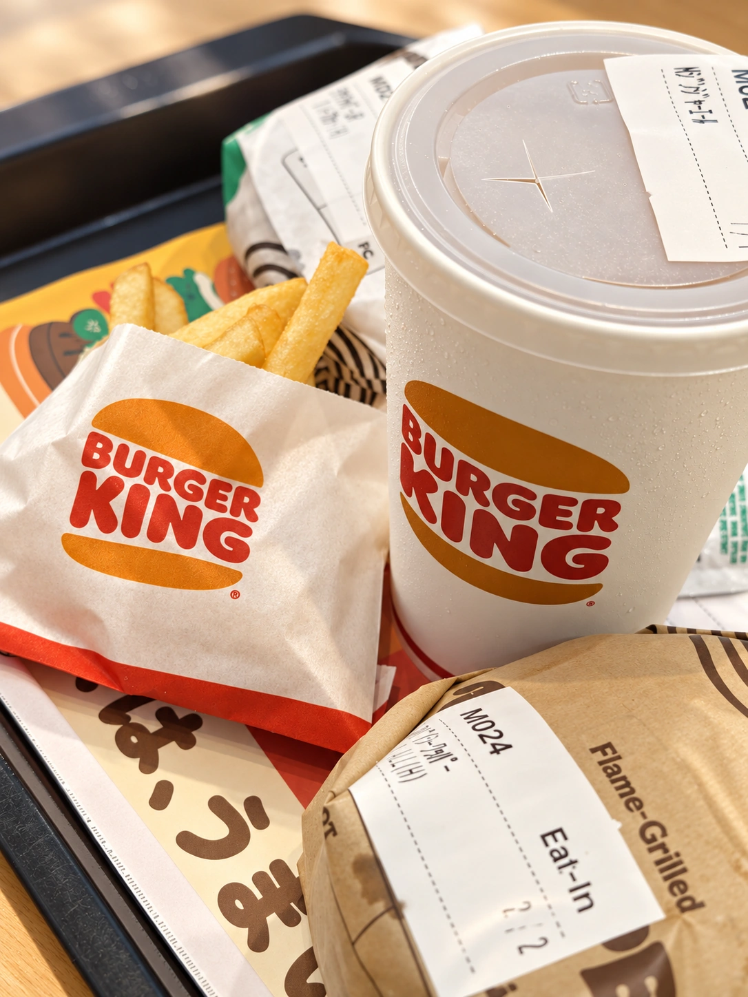 バーガーキングのトレイに、包み紙のバーガー2つとポテト、ドリンクのカップが並んでいる