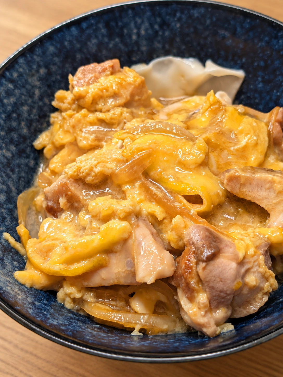 紺色の丼に盛られた、鶏肉と玉ねぎの親子丼