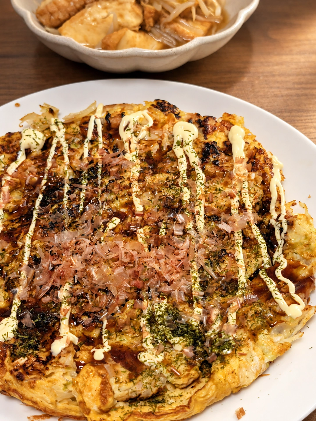 ソースやかつお節のかかったキャベツと卵の焼き物（卓上と明るさをAIで加工）