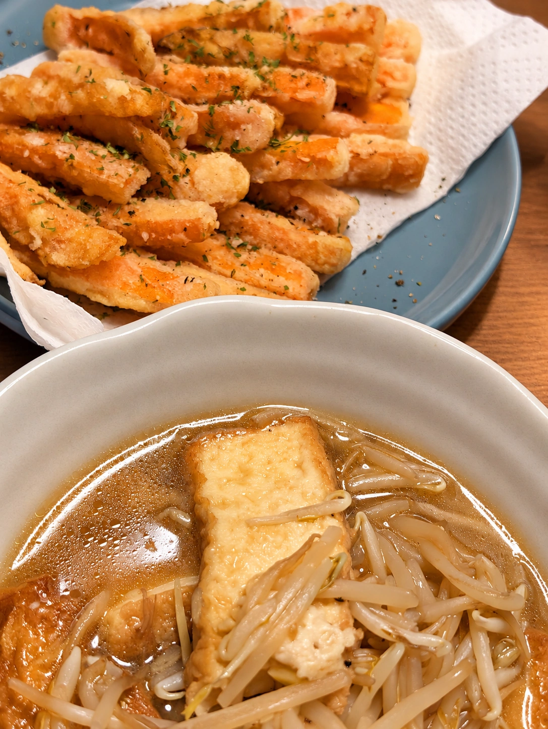 厚揚げともやしの煮物と、青い皿に盛ったごぼうの唐揚げ(卓上・照明をAIで加工)